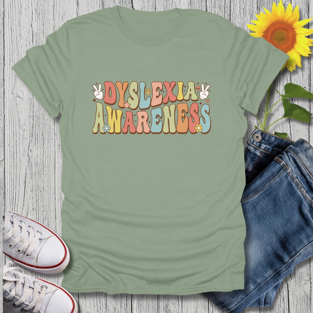 Green t-shirt with 'Dyslexia Awareness' text on a wooden surface with jeans and sneakers.