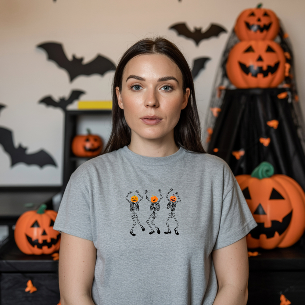 Woman wearing a gray t-shirt with skeleton and pumpkin design in a Halloween-themed room.