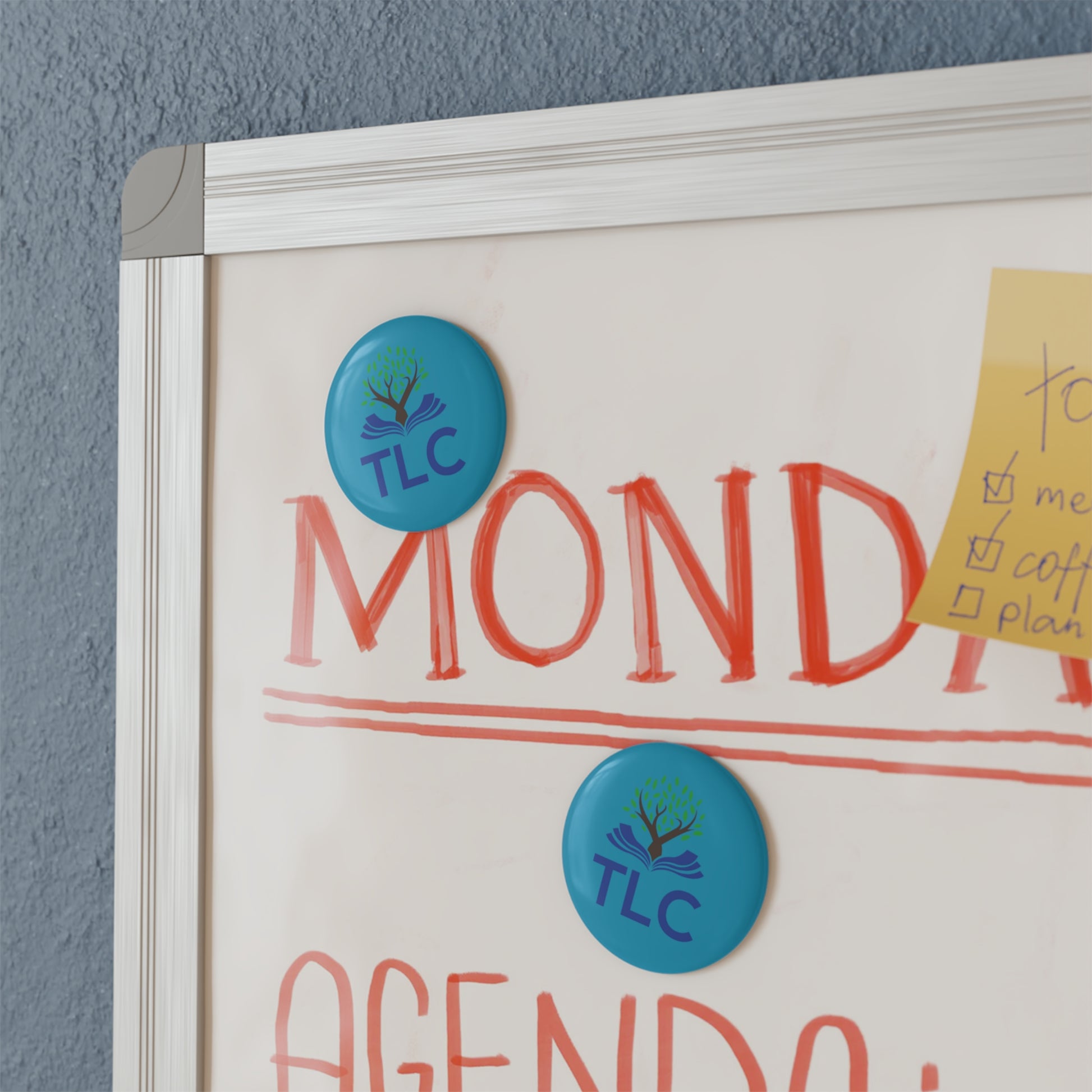 Whiteboard with 'MONDAY' and 'TLC' magnets on a gray wall