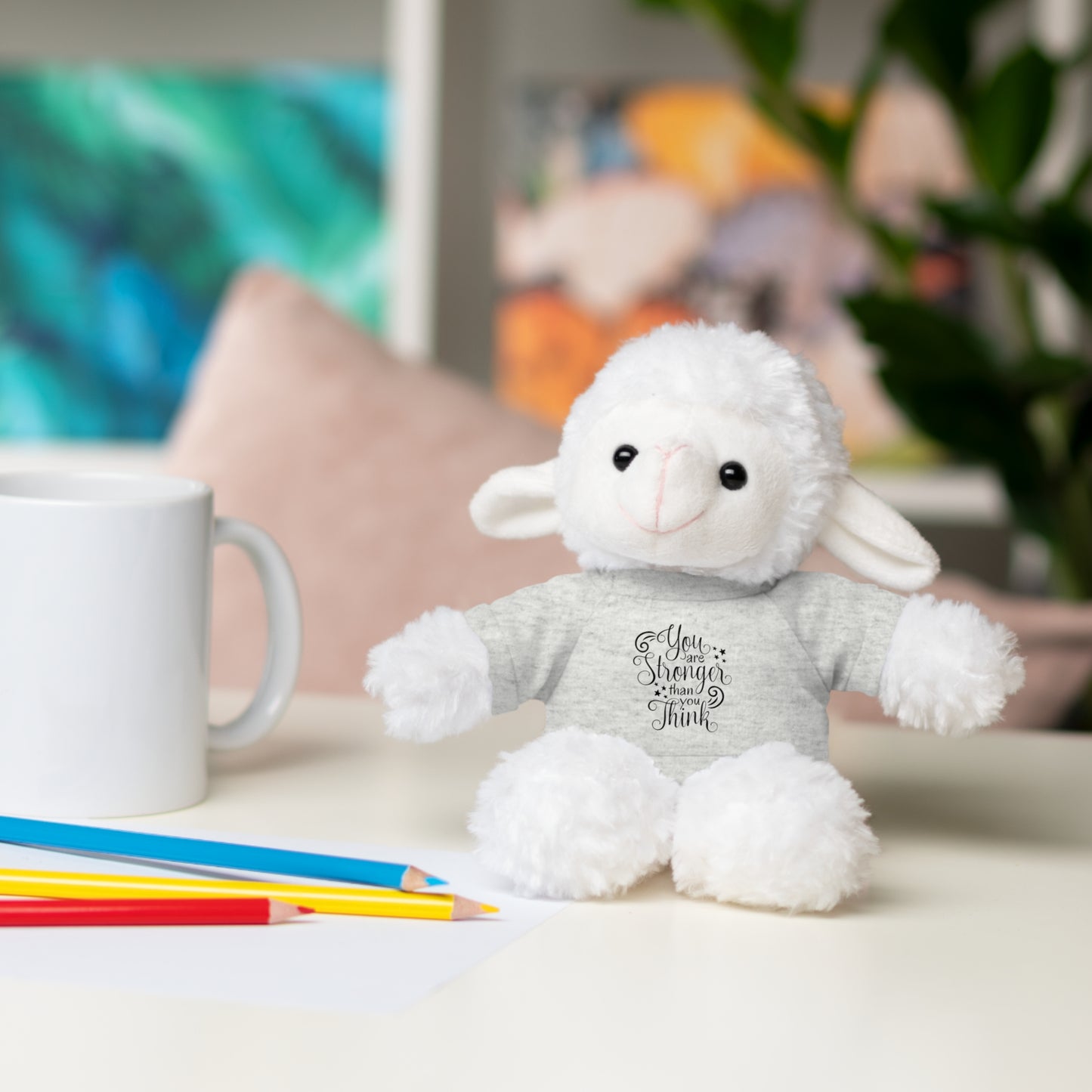 White plush toy with text on a table with a mug and pencils