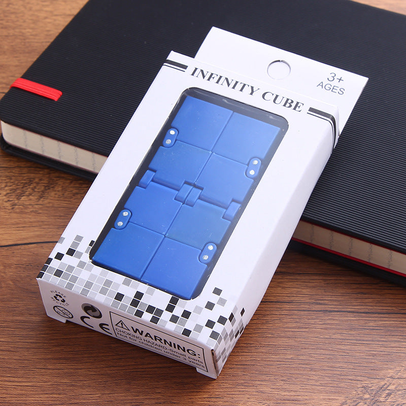 Box of 'Infinity Cube' toy on a wooden surface with a notebook in the background