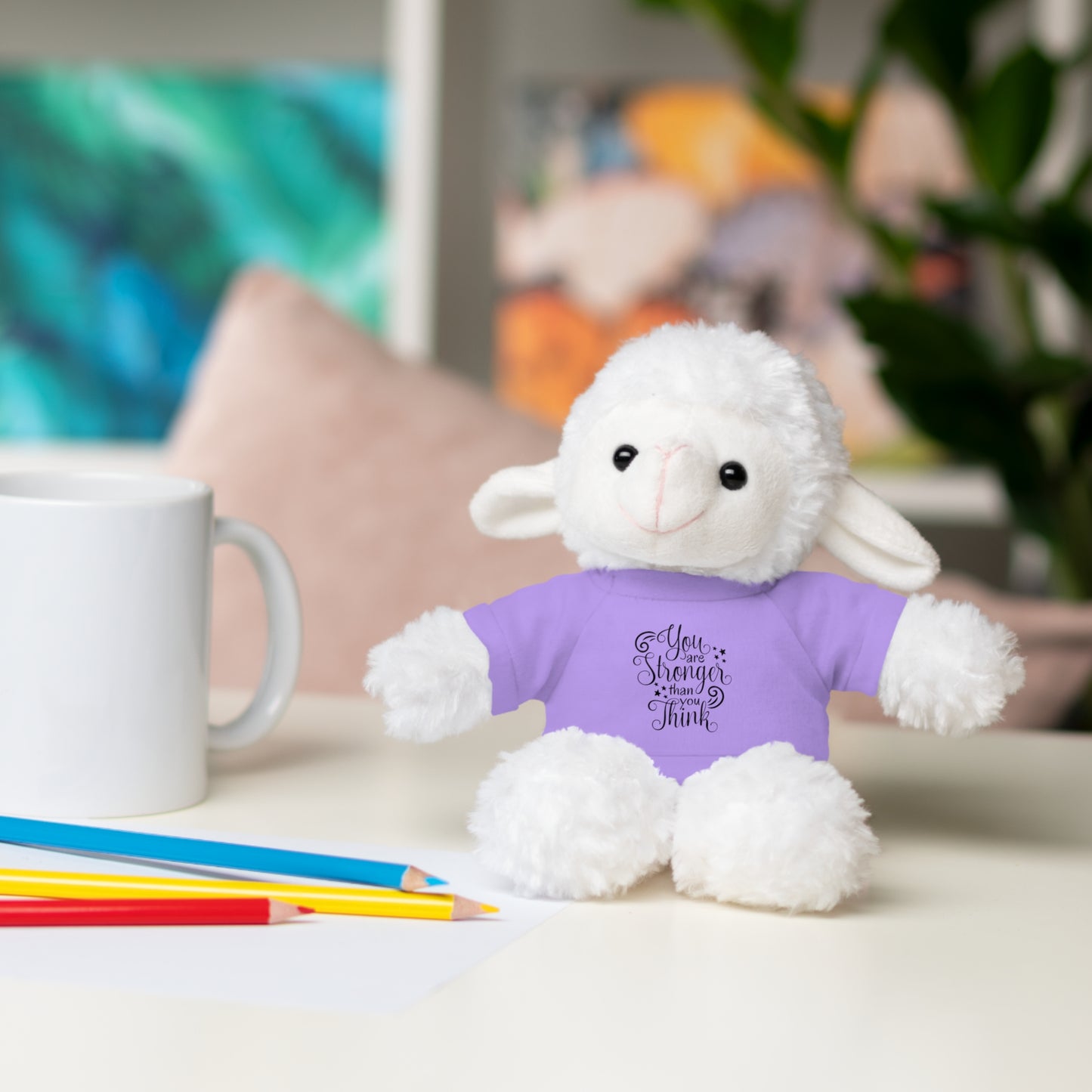 White fluffy toy with a purple shirt on a table with a mug and pencils.