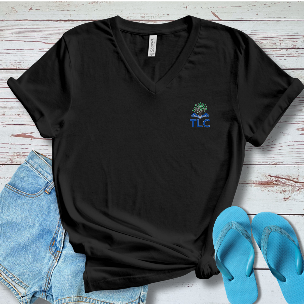 Black t-shirt with a logo, blue jeans, and blue flip-flops on a wooden surface
