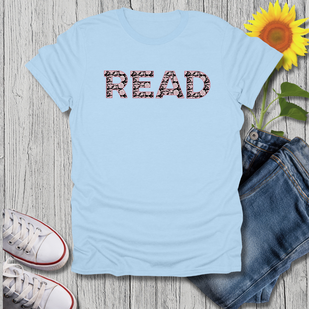 Light blue t-shirt with 'READ' printed on it, next to jeans and a sunflower on a wooden surface.