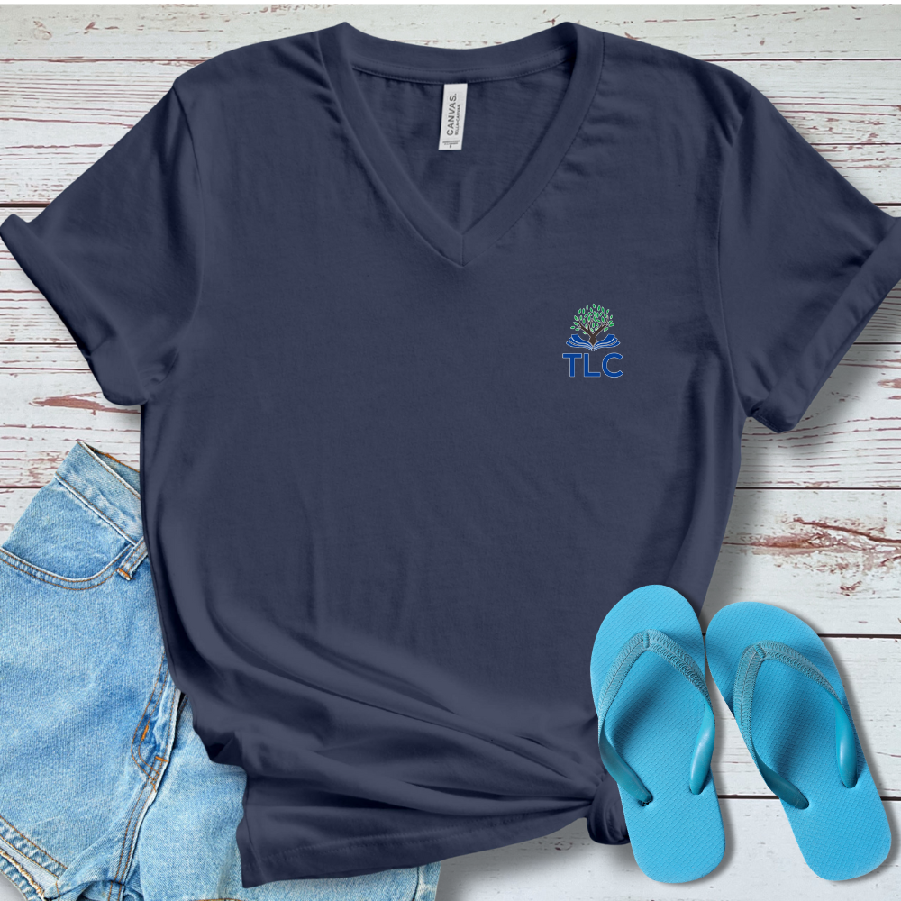 Navy blue t-shirt with a logo and text, paired with denim jeans and blue flip-flops on a wooden surface.