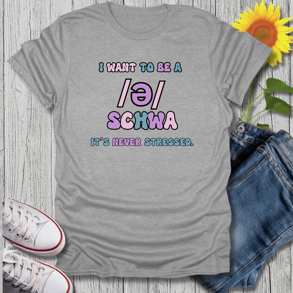 Gray t-shirt with colorful text, sunflower, jeans, and sneakers on a wooden surface