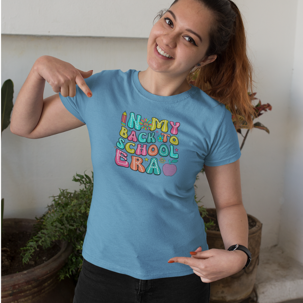 Woman wearing a blue t-shirt with colorful text, pointing to it.