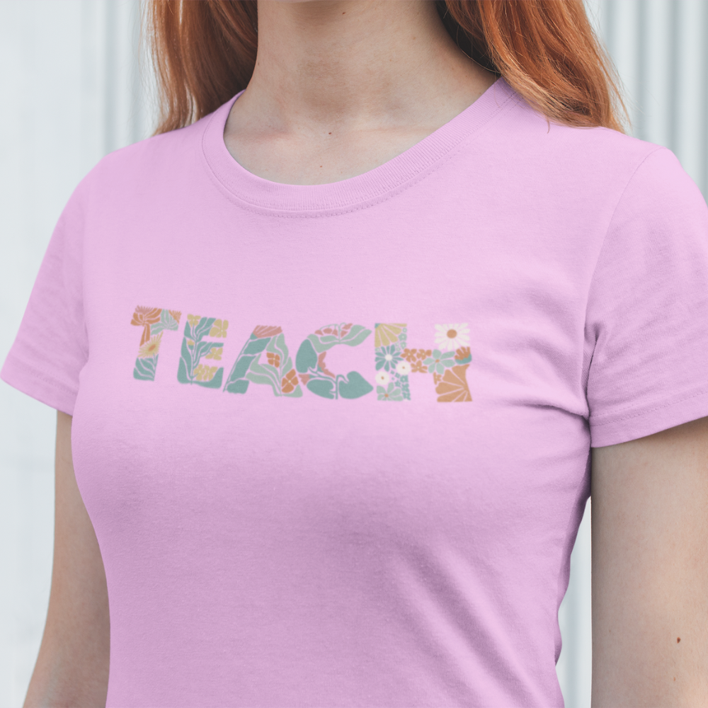 Person wearing a pink t-shirt with 'TEACH' printed on it against a white background