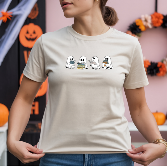 Person wearing a white t-shirt with cartoon ghosts design in front of Halloween decorations.