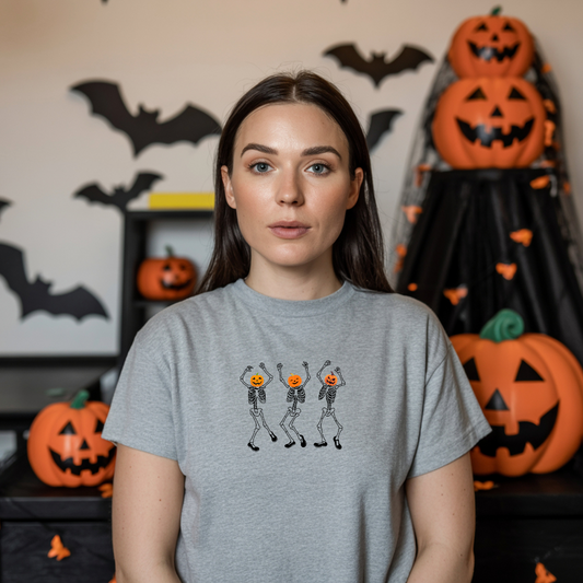 Woman wearing a gray t-shirt with skeleton and pumpkin design in a Halloween-themed room.