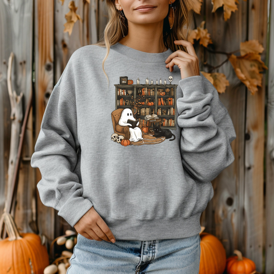 Person wearing a gray sweatshirt with a Halloween-themed design, standing in front of a wooden wall with pumpkins.