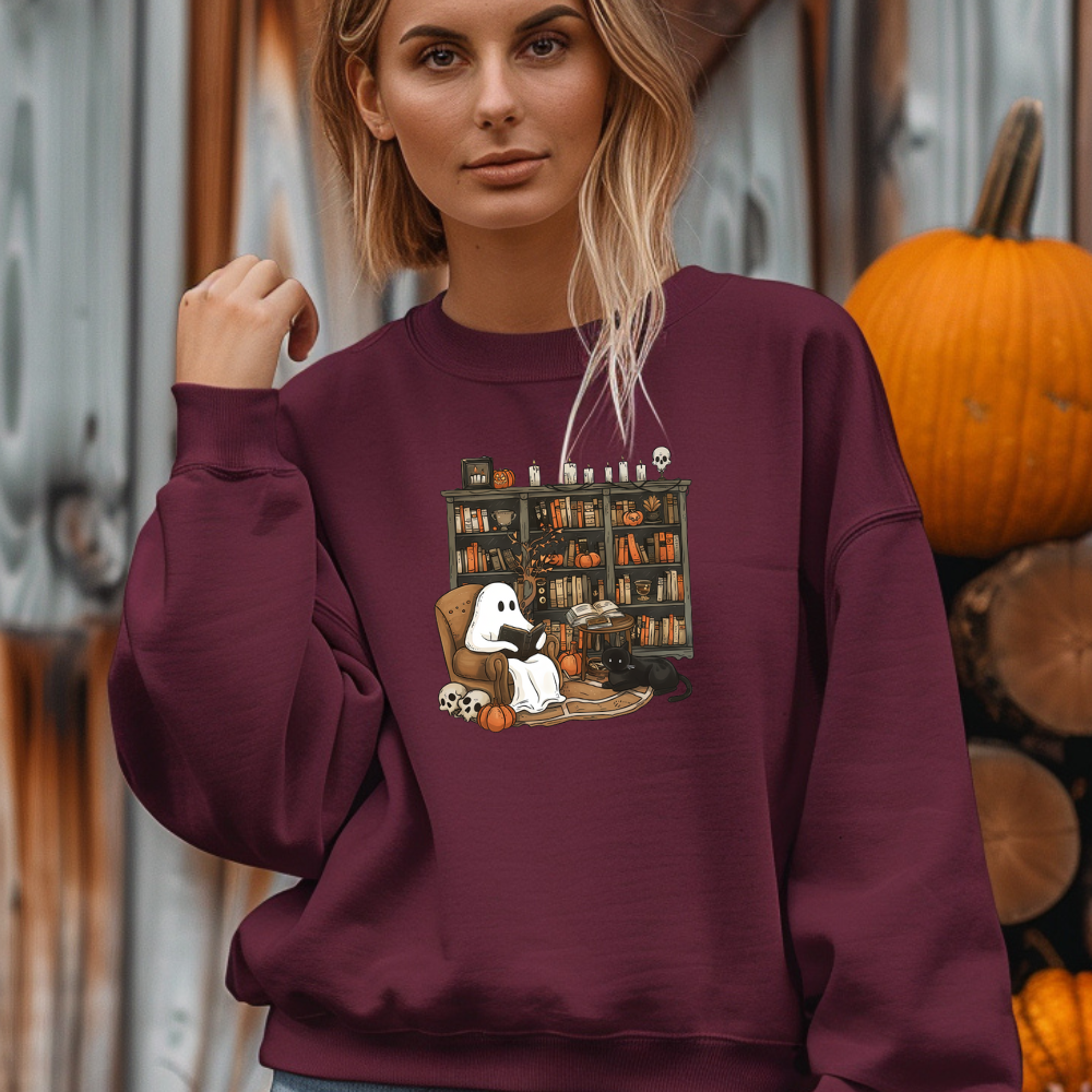 Woman wearing a maroon sweatshirt with a graphic design in an outdoor setting with pumpkins.
