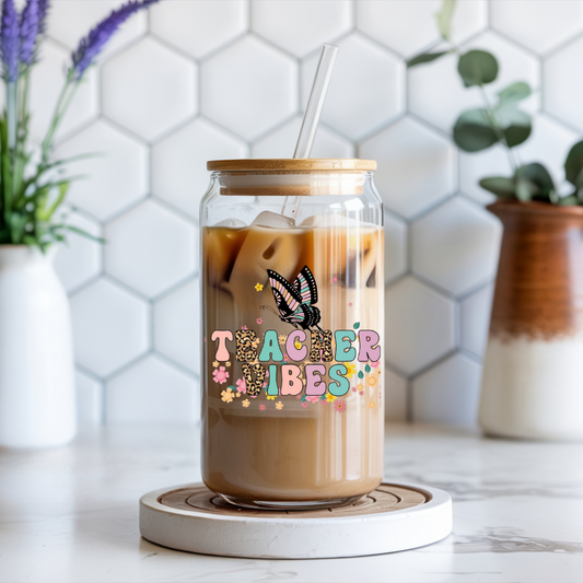 Glass jar with iced coffee and 'Teacher Vibes' design on a white hexagonal tile background.