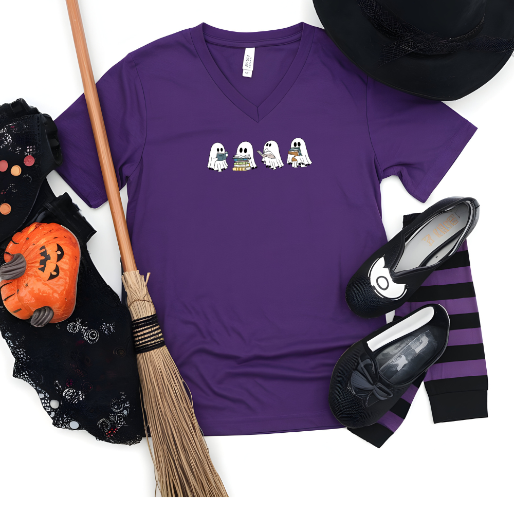 Purple t-shirt with Halloween-themed design, broom, pumpkin, shoes, and striped pants on a white background
