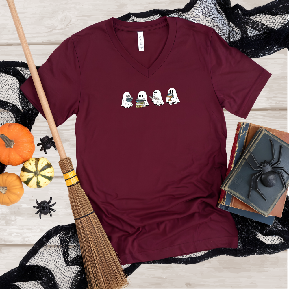 Maroon t-shirt with Halloween-themed design on a wooden surface with pumpkins and broomsticks.