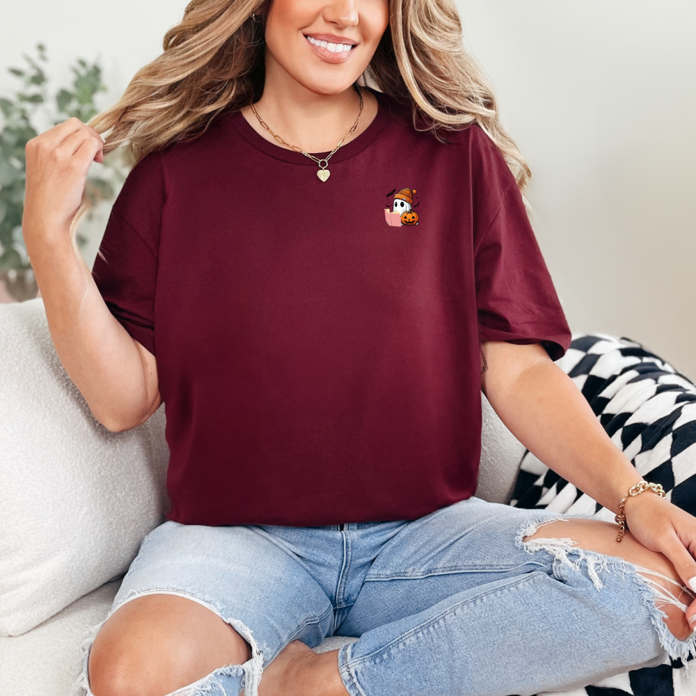 Woman wearing a burgundy t-shirt with a small graphic on a couch.