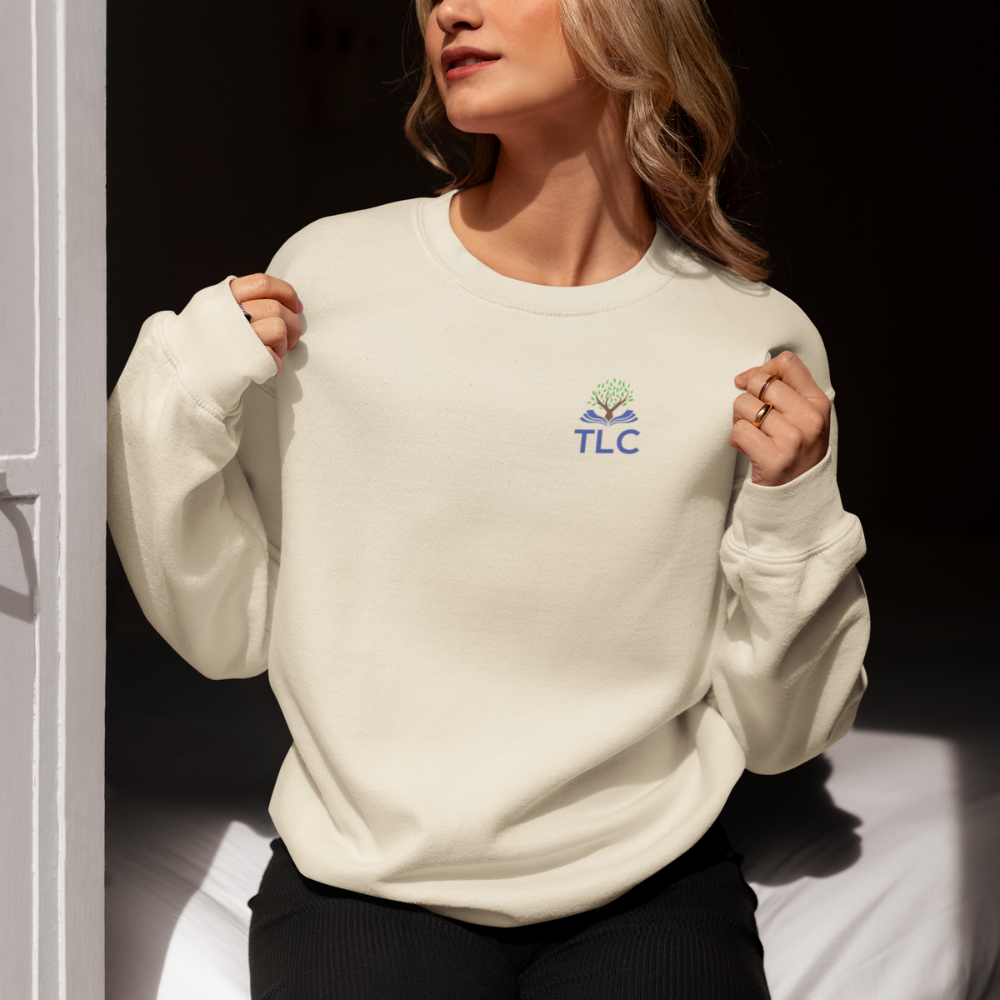 Person wearing a white sweatshirt with 'TLC' logo against a dark background