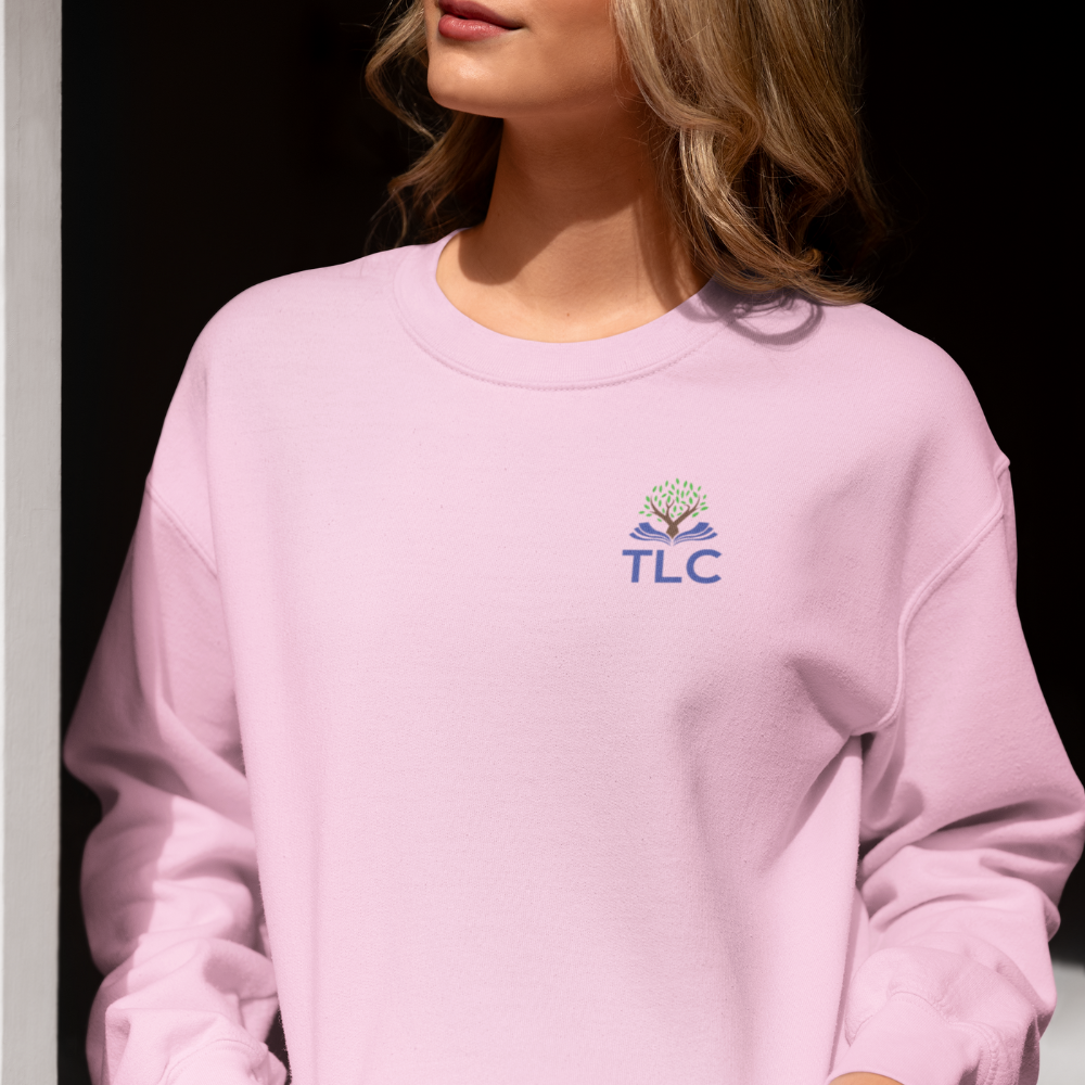 Person wearing a pink sweatshirt with a logo and 'TLC' text on a black background