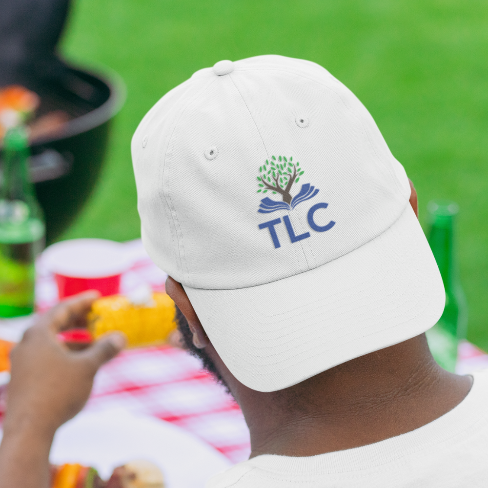 Person wearing a white cap with TLC logo at an outdoor event
