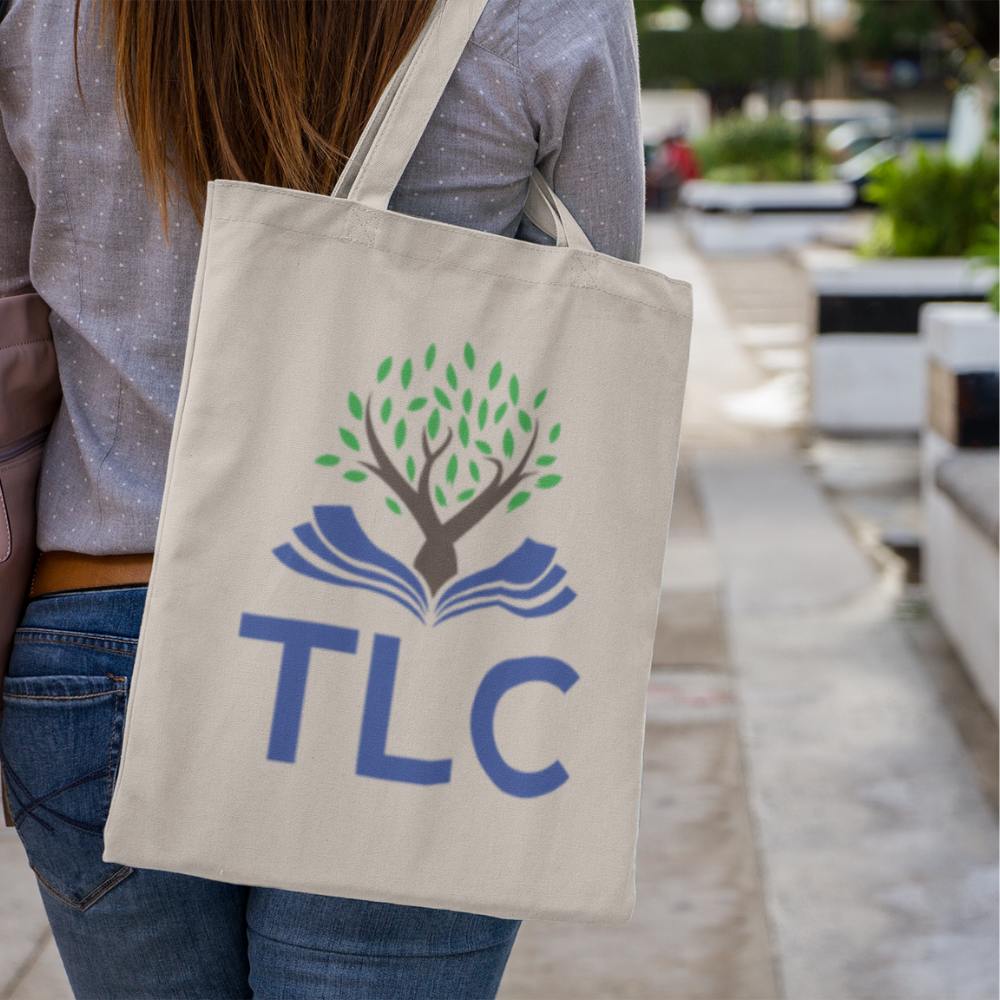 Person holding a beige tote bag with TLC logo outdoors