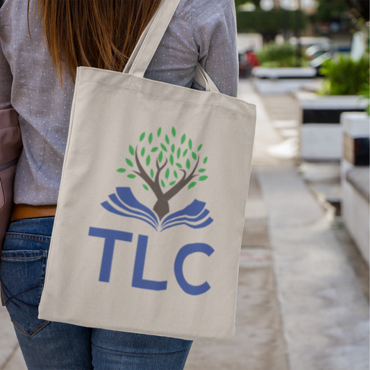 Person holding a beige tote bag with TLC logo outdoors