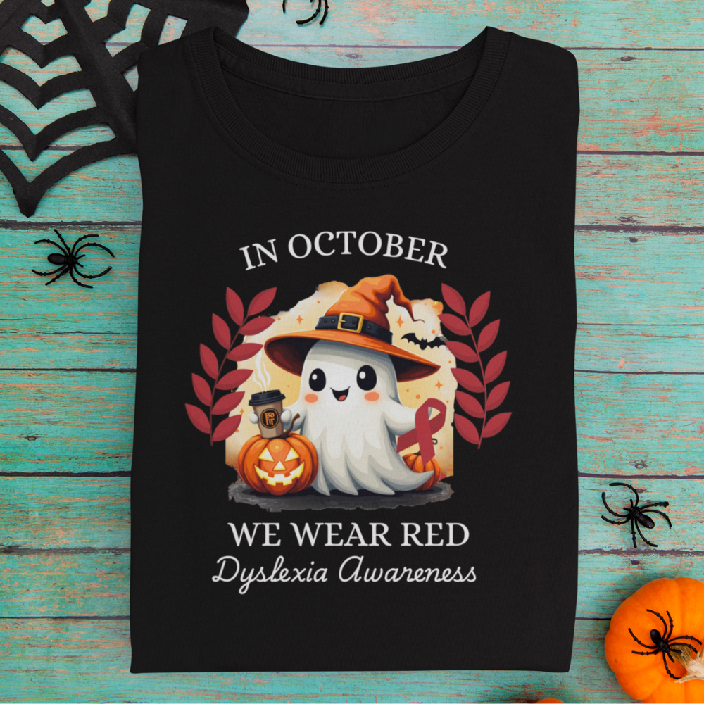 Black t-shirt with Halloween-themed design featuring a ghost, pumpkin, and text about dyslexia awareness on a wooden surface.