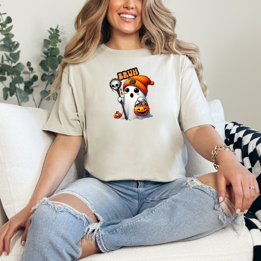 Woman wearing a beige t-shirt with cartoon ghost design sitting on a couch.