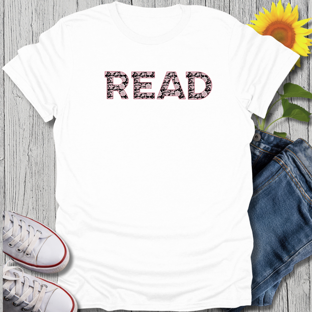 White t-shirt with 'READ' text, sunflower, jeans, and sneakers on a wooden surface