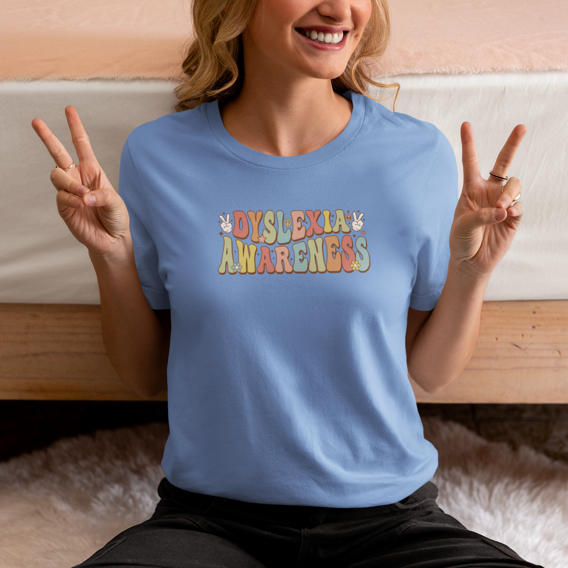 Person wearing a blue t-shirt with 'Dyslexia Awareness' text, making peace signs.